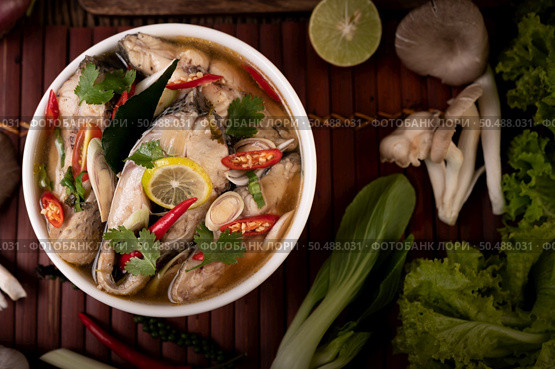 Boil the fish infusion with tomatoes, mushrooms, coriander, spring onion and lemongrass in a bowl. Стоковое фото, агентство Ingram Publishing / Фотобанк Лори