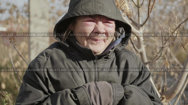 Бомж, бездомная женщина бродяга. Portrait of a homeless middle aged woman vagabond in a temporary place smiling at the camera. Стоковое видео, видеограф EStarodubov / Фотобанк Лори