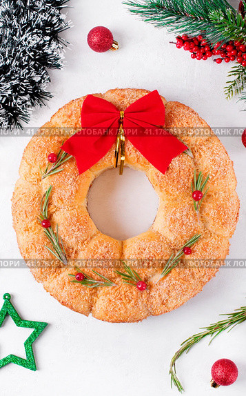 Bread Christmas wreath with cheese topped with rosemary and red berries on the white table. Festive monkey bread. Стоковое фото, фотограф Оксана Чаюн / Фотобанк Лори