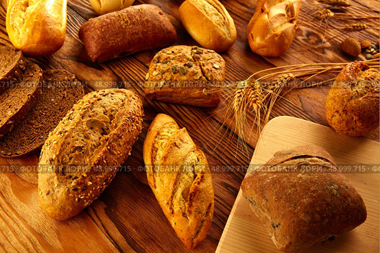 Bread fresh varied mix on golden rustic wood golden table. Стоковое фото, агентство Ingram Publishing / Фотобанк Лори