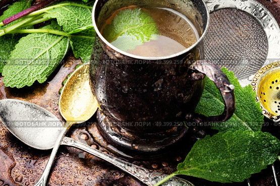 Brewed delicious herbal tea with sage on retro background.Herbal tea with sage. Cups of healthy herbal tea. Стоковое фото, агентство Ingram Publishing / Фотобанк Лори