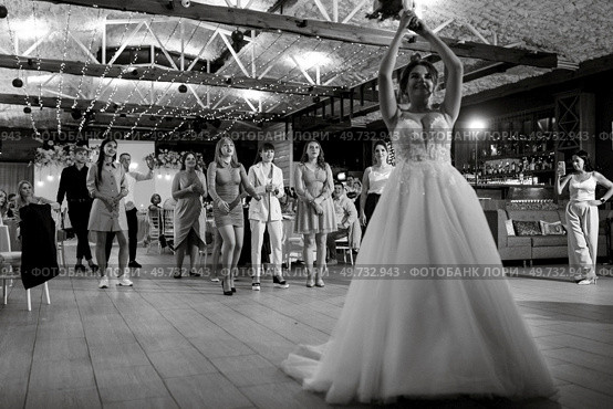 bride in a white dress throws a wedding bouquet to her unmarried girlfriends. Стоковое фото, агентство Ingram Publishing / Фотобанк Лори