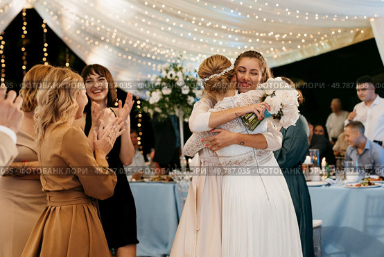bride in a white dress throws a wedding bouquet to her unmarried girlfriends. Стоковое фото, агентство Ingram Publishing / Фотобанк Лори