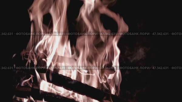 Bright flame of a burning campfire. The fire burns over stacked birch and pine firewood. Bright flame of the campfire rises high up. Tongues of yellow-orange flame wriggle. Стоковое видео, видеограф Andrew_Swarga / Фотобанк Лори