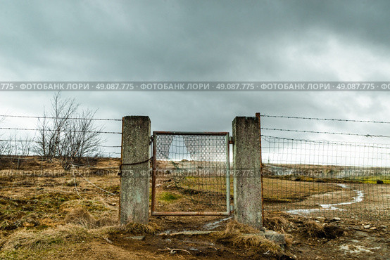 Broken gate on a field with barb wire in cloudy weather. Стоковое фото, агентство Ingram Publishing / Фотобанк Лори
