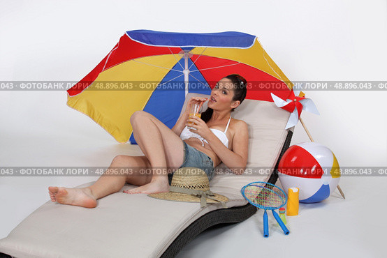 Brunette laying on lounger drinking cocktail. Стоковое фото, агентство Ingram Publishing / Фотобанк Лори