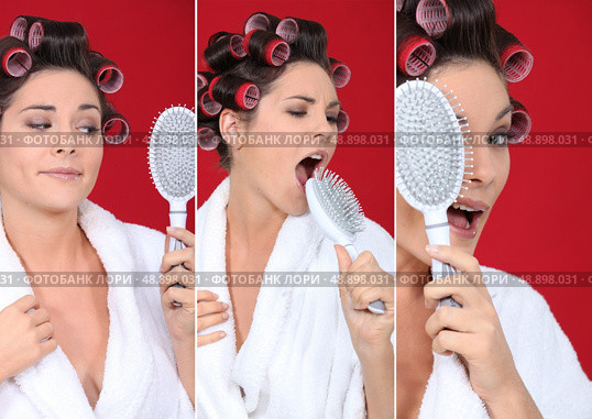 brunette wearing bathrobe with hair curlers holding hairbrush holding  against red background. Стоковое фото, агентство Ingram Publishing / Фотобанк Лори