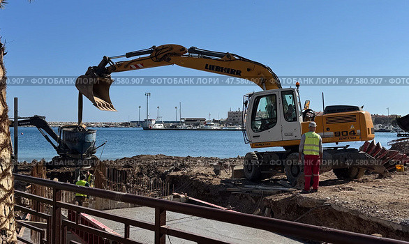 Budva,Montenegro-April 11,2025:Liebherr and Volvo excavators at a waterside. Редакционное фото, фотограф Margarita Davchenko / Фотобанк Лори