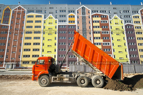 Building urban scene. Multistorey building apartment house and dump truck unload soil at day. . Стоковое фото, агентство Ingram Publishing / Фотобанк Лори