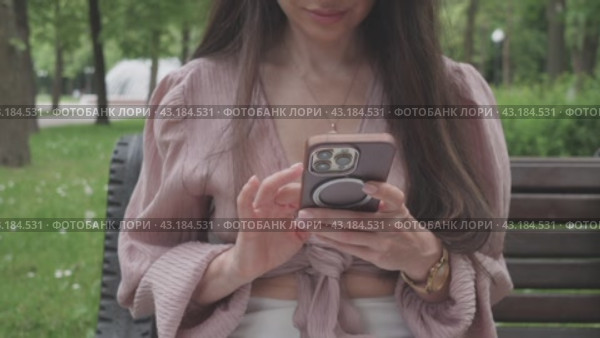 Business woman in the park in the summer writes a message on the phone. Стоковое видео, видеограф Громов Александр / Фотобанк Лори