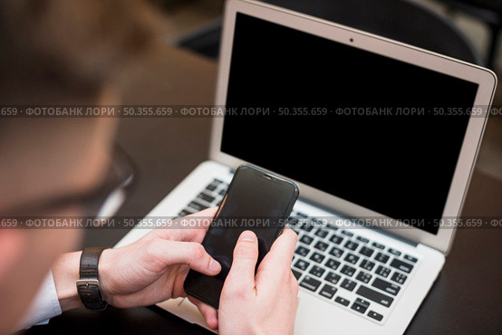 businessman s hand using mobile phone front laptop. Стоковое фото, агентство Ingram Publishing / Фотобанк Лори