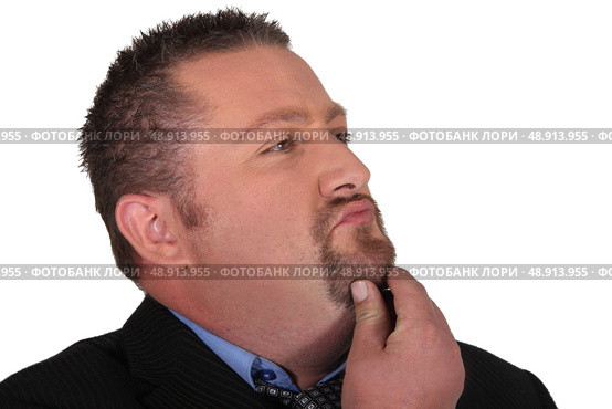 Businessman stroking his beard whilst thinking. Стоковое фото, агентство Ingram Publishing / Фотобанк Лори