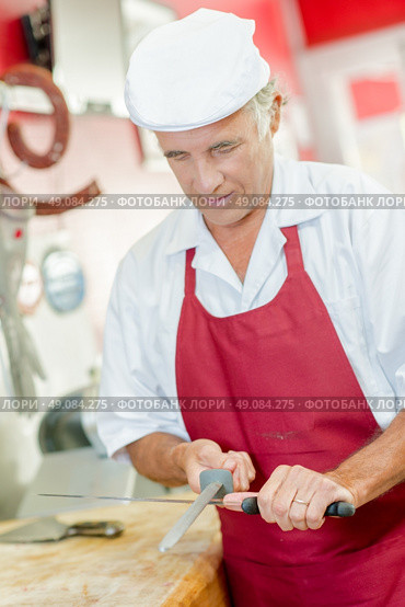 Butcher sharpening a knife. Стоковое фото, агентство Ingram Publishing / Фотобанк Лори