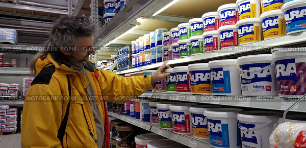 Buyer selects paint and plaster in the store (2018 год). Редакционное фото, фотограф Анна Кривицкая / Фотобанк Лори