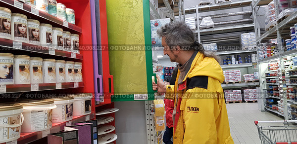 Buyer selects paint and plaster in the store (2018 год). Редакционное фото, фотограф Анна Кривицкая / Фотобанк Лори