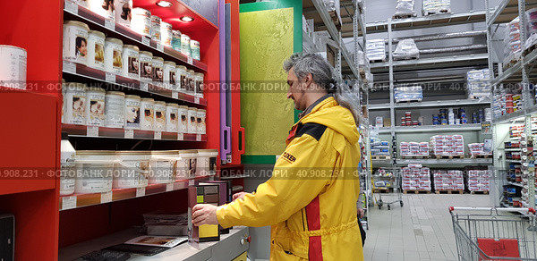 Buyer selects paint and plaster in the store (2018 год). Редакционное фото, фотограф Анна Кривицкая / Фотобанк Лори