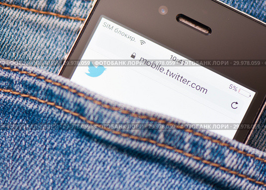Cайт Twitter на экране сотового телефона. Смартфон в кармане джинсовых штанов (2019 год). Редакционное фото, фотограф E. O. / Фотобанк Лори