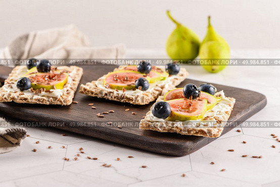 Canape or crostini with multigrain  crispread with cream cheese and fresh fig slices on a wooden board. Delicious appetizer ideal as an aperitif. Стоковое фото, агентство Ingram Publishing / Фотобанк Лори