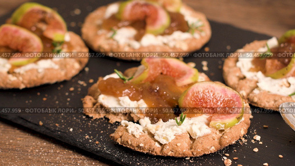 Canape or crostini with multigrain  crispread with cream cheese and fig jam on a slate board. Delicious appetizer ideal as an aperitif. Стоковое фото, агентство Ingram Publishing / Фотобанк Лори