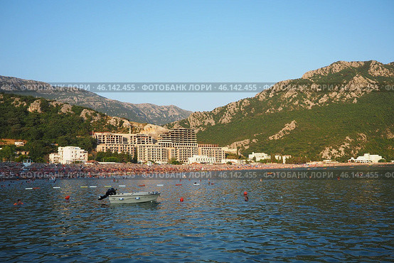 Canj, Montenegro 07.20.2024 Boats and a shore with vacationers, sunbathers and swimmers. Hotels, sun umbrellas, Adriatic waves, buoys. Beach tourism. Vacation travel. Summer day. Pebble rock beach. Редакционное фото, фотограф Юлия Петровская / Фотобанк Лори