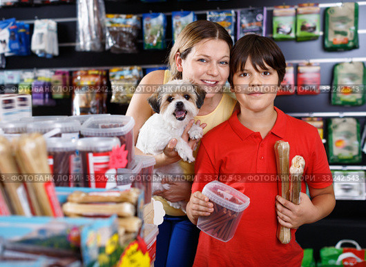 Careful preteen boy with mother visiting pet shop in search of treats for their dog. Стоковое фото, фотограф Яков Филимонов / Фотобанк Лори