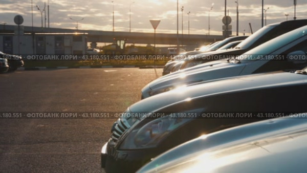 Cars in a row in the parking lot in the sunset against the background of freeway traffic. Switching from out of focus to focus. Стоковое видео, видеограф Ярославский Максим / Фотобанк Лори