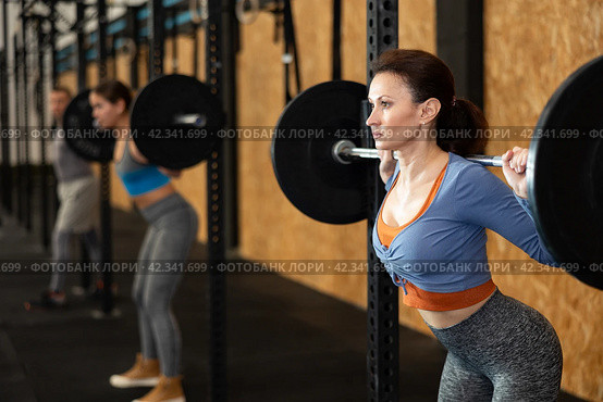 Caucasian woman training with barbell using squat rack in crossfit gym. Стоковое фото, фотограф Яков Филимонов / Фотобанк Лори