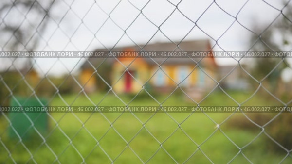 Chain link fence detail, blurring residential building behind, symbolizing boundary, privacy, protection of residential space. Стоковое видео, видеограф Mikhail Davidovich / Фотобанк Лори