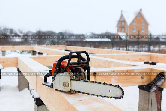 Chainsaw on wooden logs of a reinforced concrete pile foundation of a frame house. Стоковое фото, фотограф Кекяляйнен Андрей / Фотобанк Лори