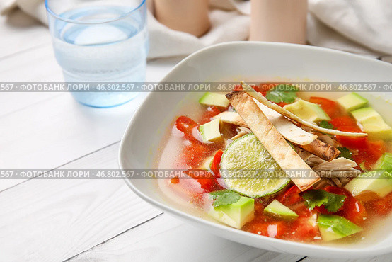Чаша с вкусным супом Сопа де Лима и стаканом воды на светлом деревянном фоне, крупным планом. Стоковое фото, фотограф Pixel_shot / Фотобанк Лори