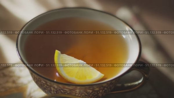 Чашка теплого чая с лимоном на декоративной тарелочке / Warm cup of tea with lemon slice on decorative saucer. Стоковое AI-видео, аниматор DeFusum / Фотобанк Лори