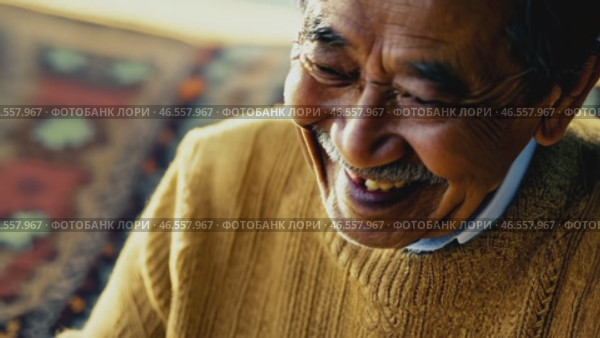Cheerful elderly Asian man with gray hair, in a yellow sweater and a shining smile looks at the camera, 4k. Advertisement of a nursing home, an active lifestyle in retirement. Стоковое видео, видеограф ALLA YURTAYEVA / Фотобанк Лори