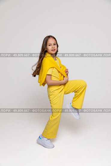 Cheerful funny genius positive little girl with curly hair in summer yellow suit has fun, jumping, dancing on white background. Happy childhood concept. Copy space. High quality photo. Стоковое фото, фотограф Ирина Михайличенко / Фотобанк Лори