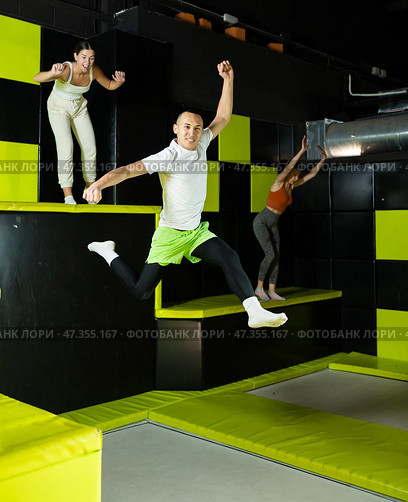 Cheerful young man jumping in modern indoor trampoline park. Стоковое фото, фотограф Яков Филимонов / Фотобанк Лори