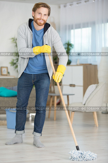 cheerful young man mopping the floor at home. Стоковое фото, агентство Ingram Publishing / Фотобанк Лори