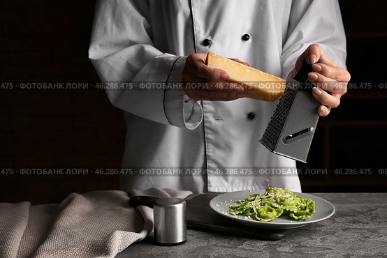 Chef grating cheese over plate with tasty ravioli. Стоковое фото, фотограф Pixel_shot / Фотобанк Лори