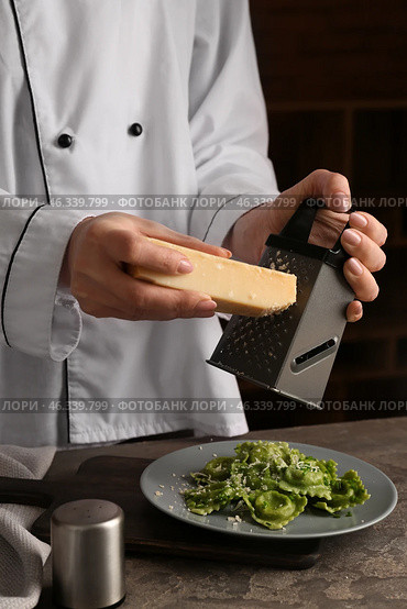 Chef grating cheese over plate with tasty ravioli. Стоковое фото, фотограф Pixel_shot / Фотобанк Лори
