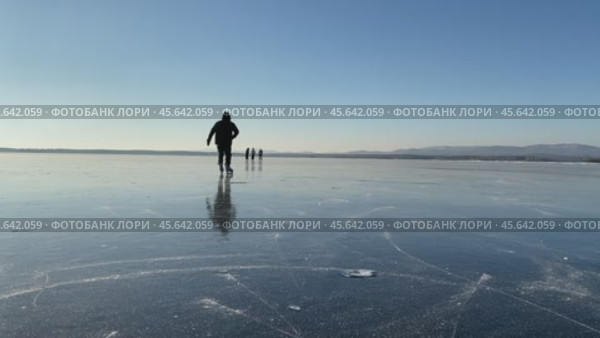Человек катается на коньках на замёрзшем озере с прозрачным льдом в ясный солнечный морозный день. Стоковое видео, видеограф Светлана Акифьева / Фотобанк Лори