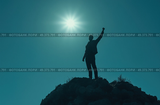 Человек на вершине горы с поднятой рукой к солнцу. Стоковое AI-изображение, AI-художник Александр Жуков / Фотобанк Лори