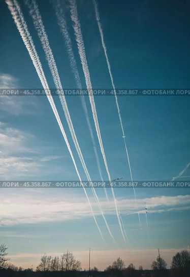 Chemtrail conspiracy theory. Long-lasting condensation trails left in sky by high-flying aircraft are actually chemtrails consisting of chemical or biological agents, sprayed for nefarious purposes. Стоковое AI-изображение, AI-художник Юлия Петровская / Фотобанк Лори