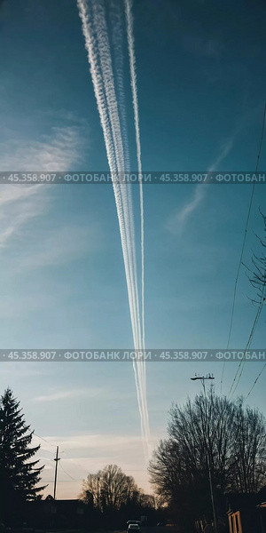 Chemtrail conspiracy theory. Long-lasting condensation trails left in sky by high-flying aircraft are actually chemtrails consisting of chemical or biological agents, sprayed for nefarious purposes. Стоковое AI-изображение, AI-художник Юлия Петровская / Фотобанк Лори