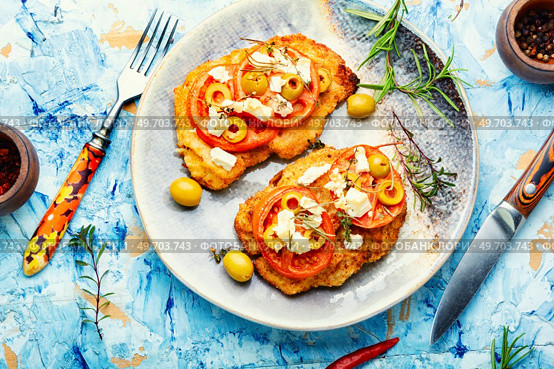 Chicken schnitzel with piece tomato, olives and cheese. Healthy keto. Top view. Tasty breaded chicken meat steaks. Стоковое фото, агентство Ingram Publishing / Фотобанк Лори