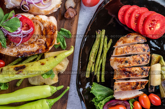 Chicken steak put on a black plate, add bell peppers, tomatoes, red onions, pineapple sauce, lettuce and sesame. Стоковое фото, агентство Ingram Publishing / Фотобанк Лори