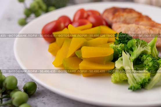 Chicken steak topped with white sesame, peas, tomatoes, broccoli and pumpkin in a white plate. Стоковое фото, агентство Ingram Publishing / Фотобанк Лори