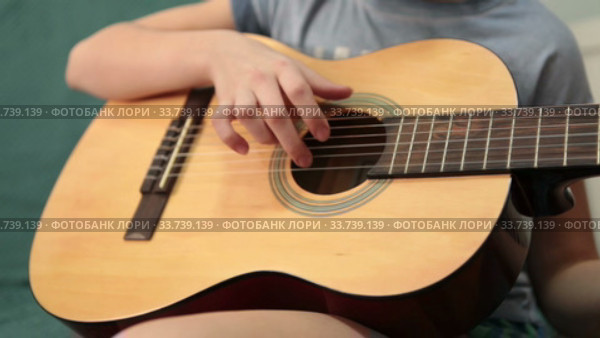 Children hand pluck the strings and fretboard of a yellow acoustic guitar, close up view (2020 год). Редакционное видео, видеограф Кекяляйнен Андрей / Фотобанк Лори