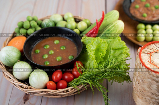 Chili paste paste in a bowl with eggplant, carrots, chili, cucumbers in a basket on wood table. Стоковое фото, агентство Ingram Publishing / Фотобанк Лори