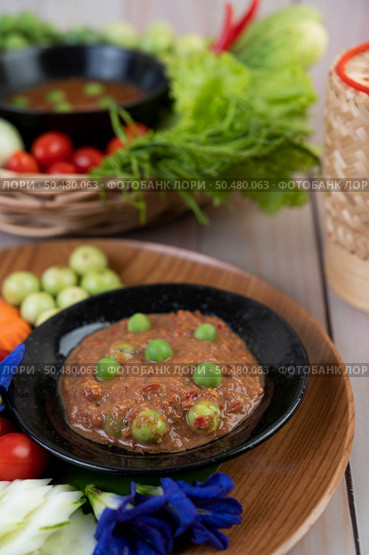 Chili paste paste in a bowl with eggplant, carrots, chili, cucumbers in a basket on wood table. Стоковое фото, агентство Ingram Publishing / Фотобанк Лори