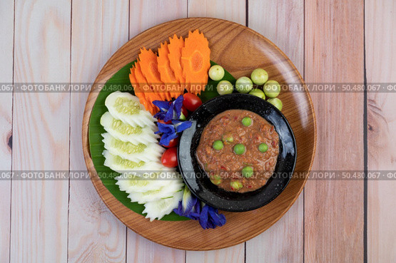Chili paste paste in a bowl with eggplant, carrots, chili, cucumbers in a basket on wood table. Стоковое фото, агентство Ingram Publishing / Фотобанк Лори