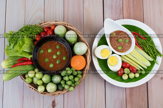 Chili paste paste in a bowl with eggplant, carrots, chili, cucumbers in a basket on wood table. Стоковое фото, агентство Ingram Publishing / Фотобанк Лори