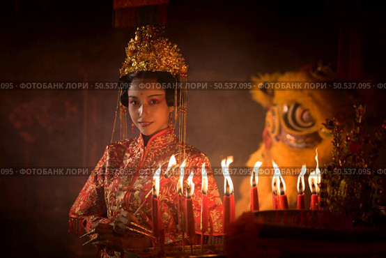 Chinese woman make wishes, pray, and light candles. On the occasion of the annual Chinese New Year festival, in a revered shrine or temple, And in Chinese where candles mean good luck and happiness. Стоковое фото, агентство Ingram Publishing / Фотобанк Лори